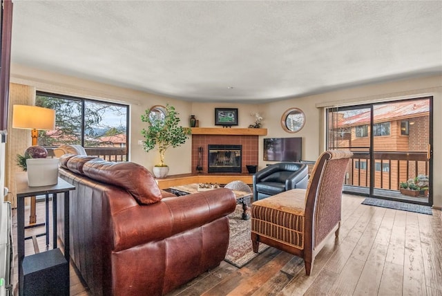 living area with a tiled fireplace, hardwood / wood-style flooring, and a textured ceiling