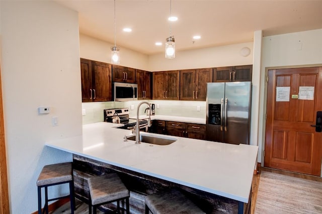 23110 US Highway 6 Unit 319, Keystone, CO 80435 - kitchen featuring stainless steel appliances, tasteful backsplash, dark brown cabinets, a breakfast bar area, and light countertops