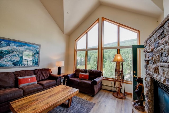23110 US Highway 6 Unit 319, Keystone, CO 80435 - living room featuring a baseboard radiator, lofted ceiling, light wood-type flooring, plenty of natural light, and a stone fireplace