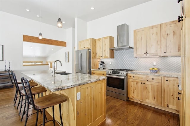 33 Hargrove Way, Silverthorne, CO 80498 - kitchen featuring wall chimney range hood, a sink, light brown cabinetry, a breakfast bar area, and appliances with stainless steel finishes