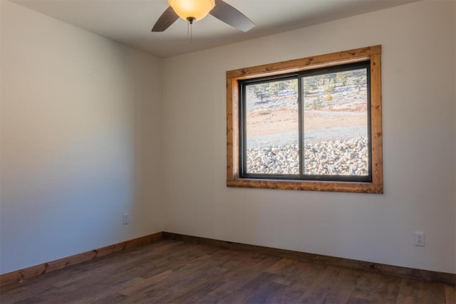 spare room featuring a ceiling fan, baseboards, and dark wood-style flooring