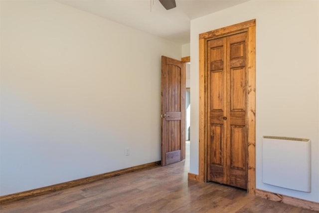 unfurnished room featuring wood finished floors, a ceiling fan, and baseboards