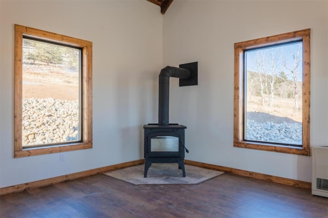 interior details with wood finished floors, a wood stove, and baseboards