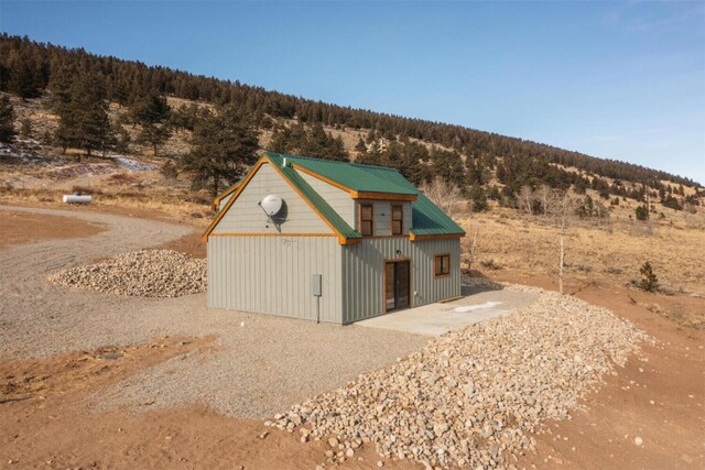 view of side of property featuring an outbuilding and a wooded view
