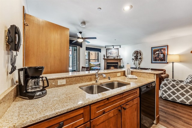 kitchen with light stone counters, ceiling fan, sink, hardwood / wood-style floors, and black dishwasher