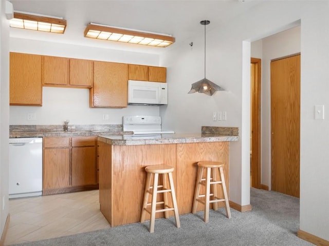 kitchen featuring hanging light fixtures, white appliances, a breakfast bar area, a peninsula, and baseboards
