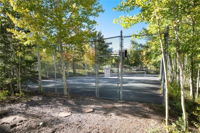 view of tennis court featuring a gate and fence