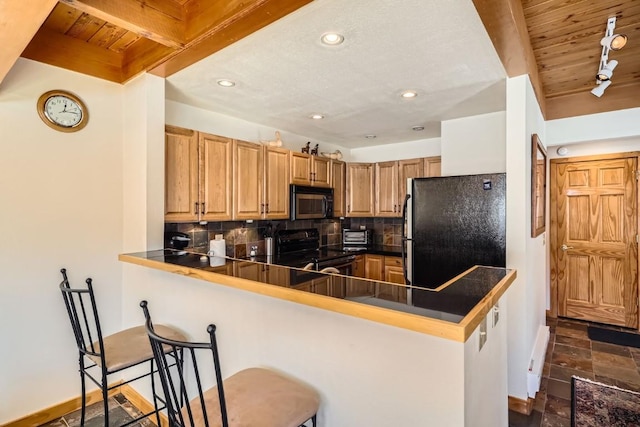 kitchen with a peninsula, recessed lighting, decorative backsplash, black appliances, and a breakfast bar area