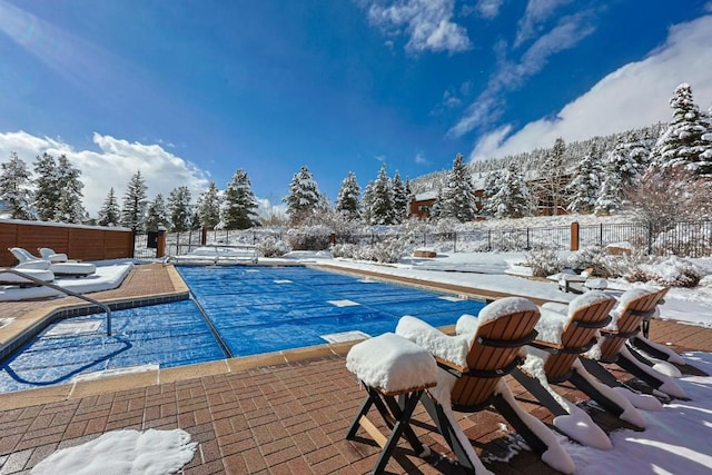 snow covered pool featuring a community pool, a patio, and fence