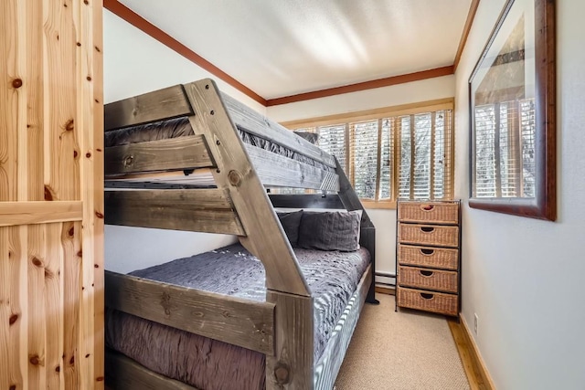carpeted bedroom with a baseboard radiator, baseboards, and ornamental molding