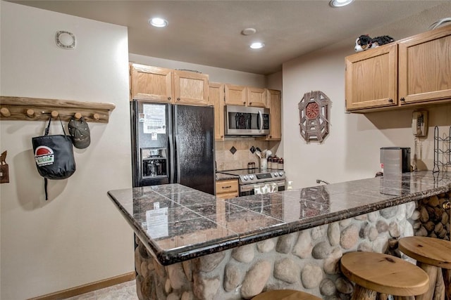 100 S Park Ave Unit E113, Breckenridge, CO 80424 - kitchen featuring stainless steel appliances, a breakfast bar, light brown cabinets, a peninsula, and tile countertops