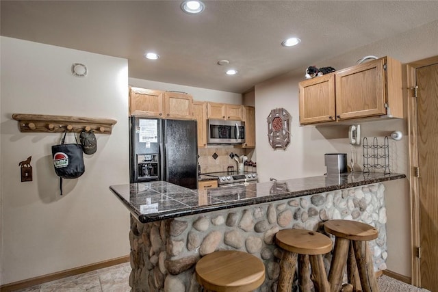 100 S Park Ave Unit E113, Breckenridge, CO 80424 - kitchen with appliances with stainless steel finishes, a peninsula, a breakfast bar area, backsplash, and tile counters