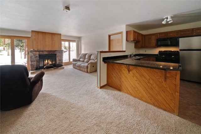 kitchen featuring a peninsula, a wealth of natural light, a sink, and black appliances