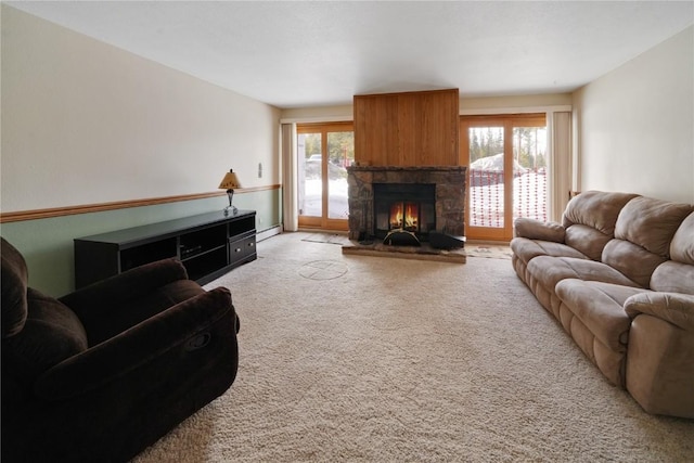 carpeted living room featuring a stone fireplace, a baseboard radiator, and a healthy amount of sunlight