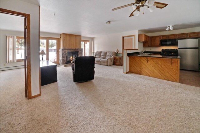 kitchen with a peninsula, dark countertops, brown cabinets, a sink, and black appliances