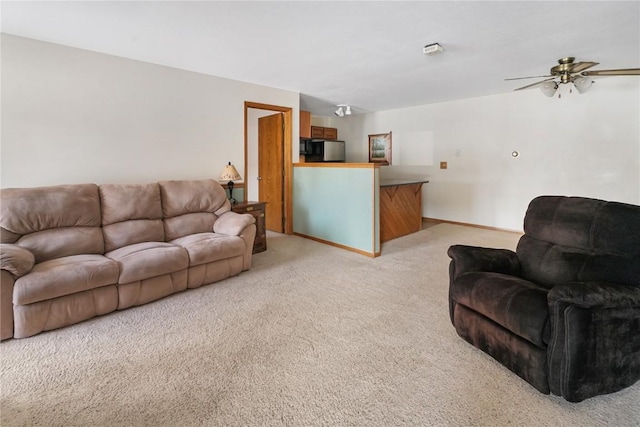 living room with baseboards, light carpet, and a ceiling fan