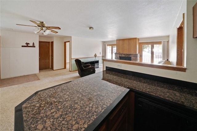 kitchen featuring light carpet, dishwasher, a fireplace, tile countertops, and open floor plan