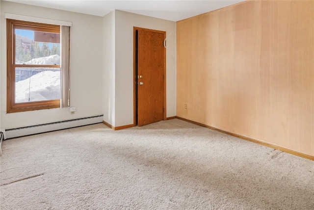 unfurnished room featuring baseboards, carpet, and a baseboard heating unit
