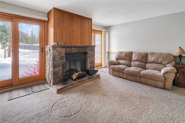 carpeted living area with a stone fireplace and a healthy amount of sunlight