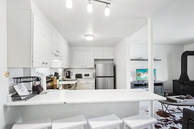 180 Evergreen Rd Unit 102, Dillon, CO 80435 - kitchen featuring a wood stove, a sink, freestanding refrigerator, white microwave, and a peninsula