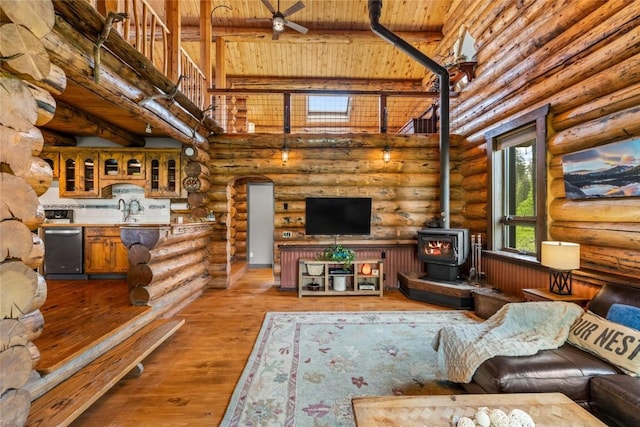 33000 Maricopa Trl, Oak Creek, CO 80467 - living area featuring rustic walls, a wood stove, a wooden ceiling with exposed beams, light wood-type flooring, and a towering ceiling