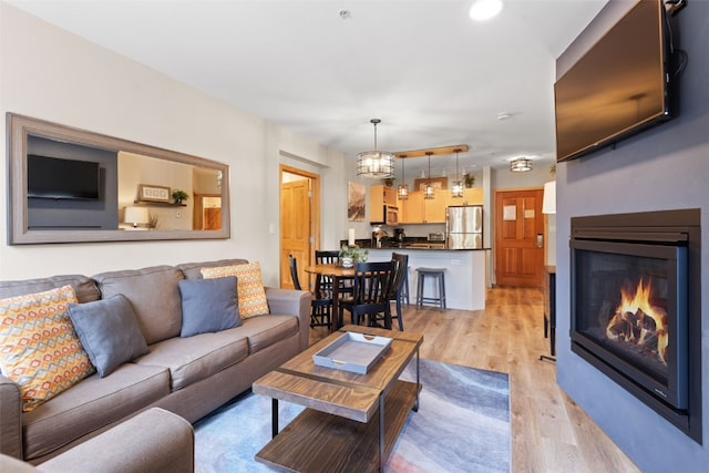 living area featuring a glass covered fireplace, light wood finished floors, and recessed lighting