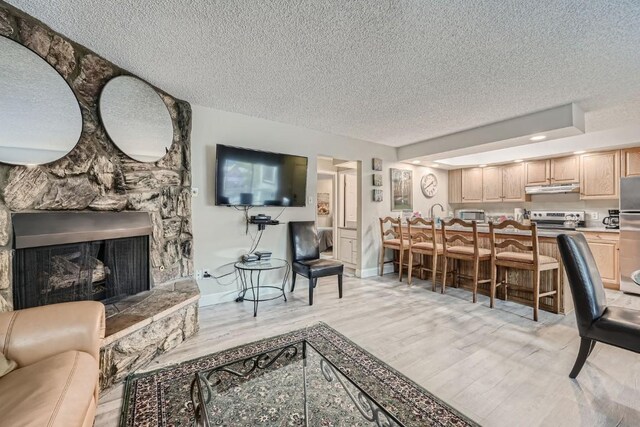 412 S Main St Unit 215, Breckenridge, CO 80424 - living area with light wood-style floors, a stone fireplace, a textured ceiling, and baseboards