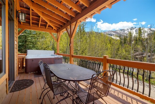 2760 Burgess Creek Rd Unit 2, Steamboat Springs, CO 80487 - deck featuring outdoor dining area, a mountain view, a hot tub, and a view of trees
