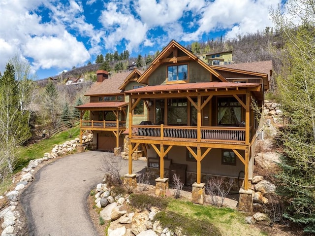 2760 Burgess Creek Rd Unit 2, Steamboat Springs, CO 80487 - exterior space with a chimney, a wooden deck, aphalt driveway, and a garage