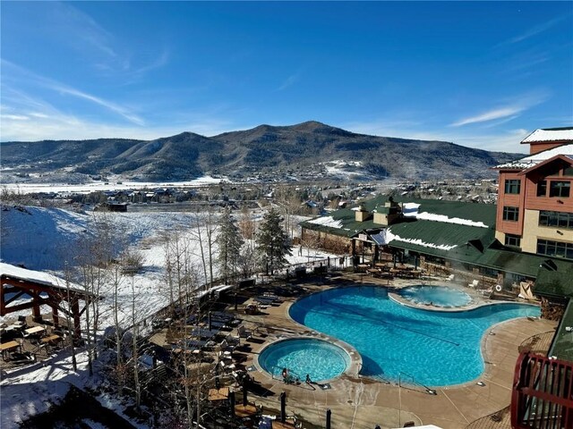 2300 Mount Werner Cir Unit 631, Steamboat Springs, CO 80487 - snow covered pool with a mountain view and a pool with connected hot tub
