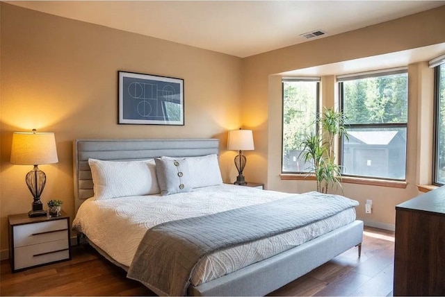 bedroom with visible vents, baseboards, and wood finished floors