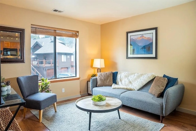 living room featuring visible vents, baseboards, and wood finished floors