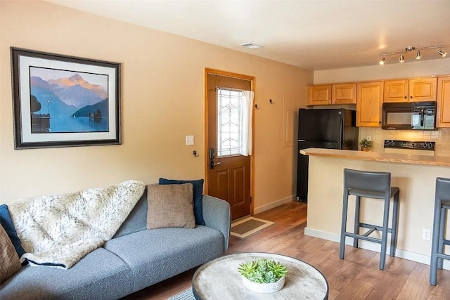 living area with light wood finished floors, visible vents, and baseboards