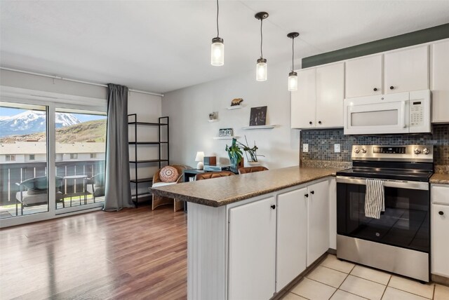 753 Straight Creek Dr Unit 304, Dillon, CO 80435 - kitchen featuring stainless steel range with electric cooktop, white microwave, a peninsula, decorative backsplash, and white cabinets