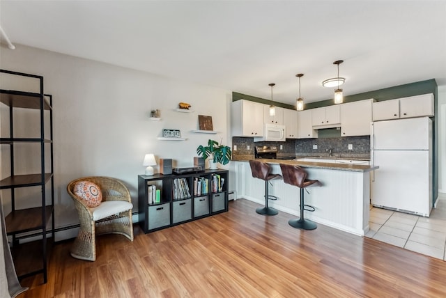 753 Straight Creek Dr Unit 304, Dillon, CO 80435 - kitchen featuring white appliances, decorative backsplash, light wood-type flooring, and a peninsula