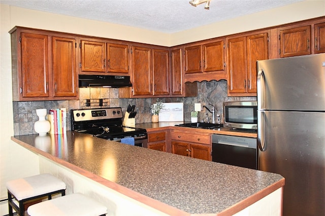 0893 Straight Creek Dr Unit 302, Dillon, CO 80435 - kitchen with appliances with stainless steel finishes, under cabinet range hood, a peninsula, dark countertops, and decorative backsplash
