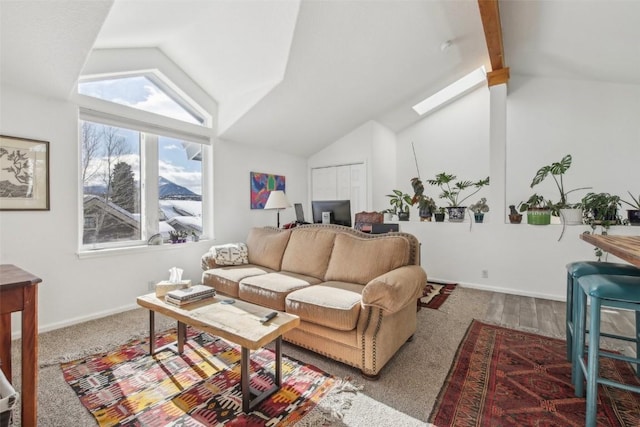 carpeted living room featuring baseboards and vaulted ceiling with skylight
