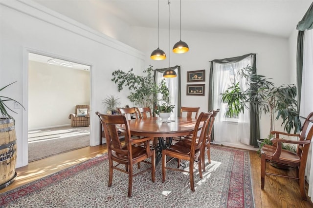 dining space with vaulted ceiling and wood finished floors