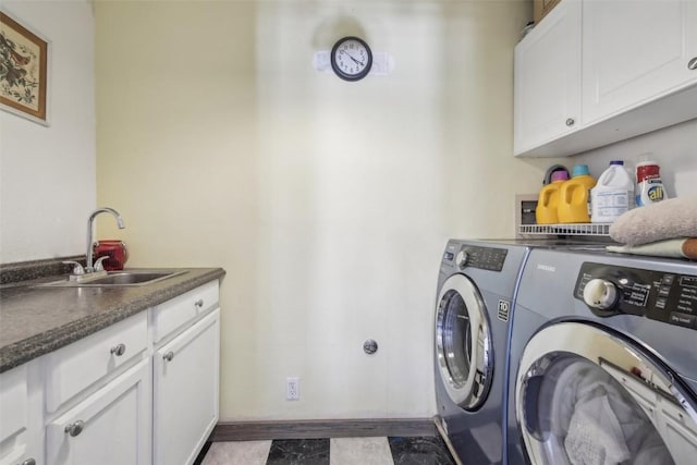 clothes washing area featuring washing machine and clothes dryer, cabinet space, a sink, and baseboards