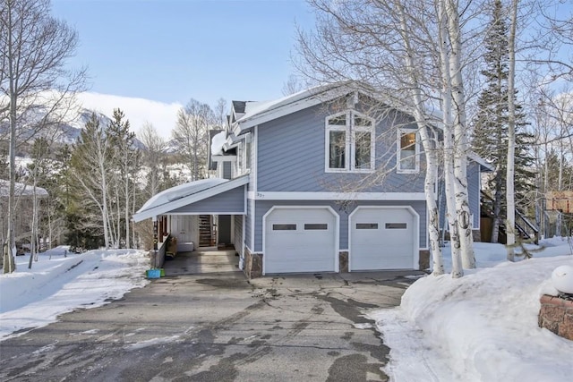 view of snowy exterior featuring driveway and a garage