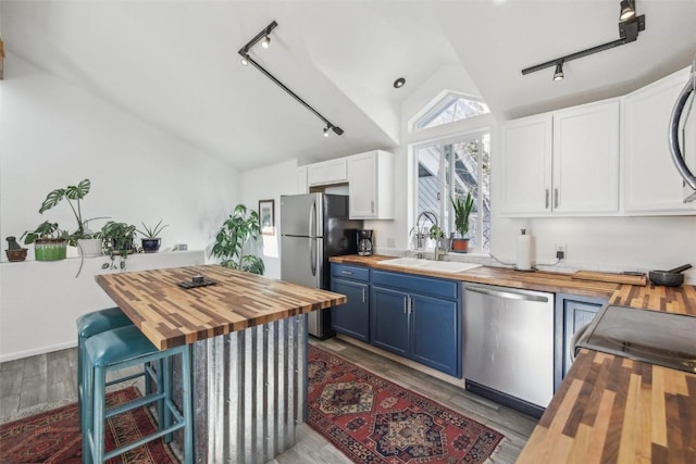 kitchen featuring track lighting, wood counters, and appliances with stainless steel finishes