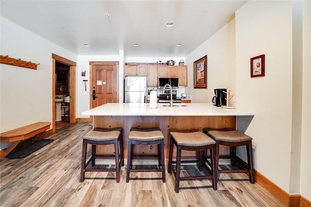 kitchen with a peninsula, appliances with stainless steel finishes, a sink, and a kitchen breakfast bar