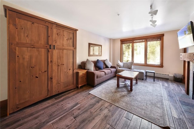 living room featuring dark wood-style floors, baseboard heating, and a fireplace with raised hearth