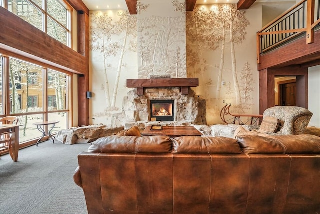 carpeted living room featuring a stone fireplace, beamed ceiling, and a towering ceiling