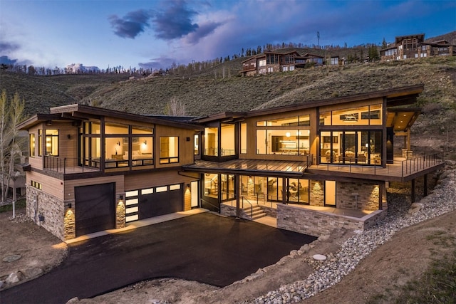 18 Heather Way, Silverthorne, CO 80498 - back of property at dusk featuring stone siding, a garage, and asphalt driveway