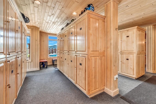 hall with baseboards, dark colored carpet, wood walls, and wood ceiling
