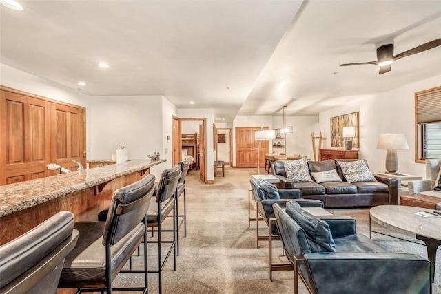 living room with ceiling fan, bar area, recessed lighting, and light colored carpet
