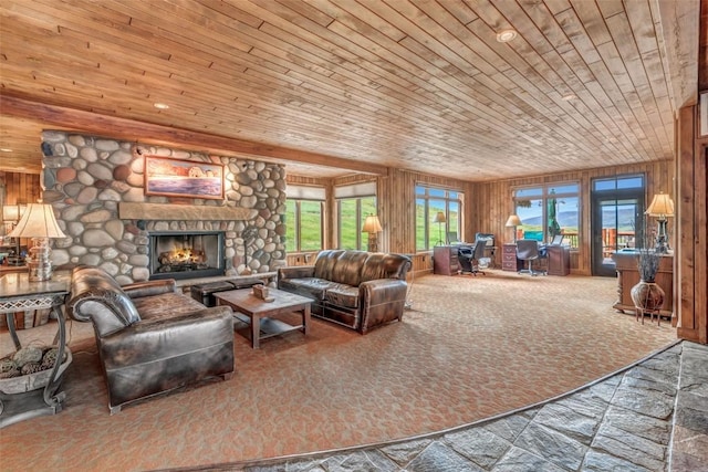 carpeted living area with wooden ceiling, a stone fireplace, and wooden walls