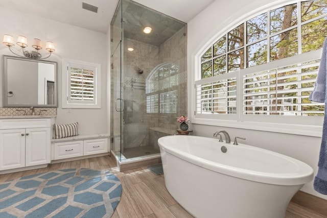 1031 Steamboat Blvd, Steamboat Springs, CO 80487 - full bath featuring vanity, a shower stall, a freestanding tub, wood finished floors, and backsplash