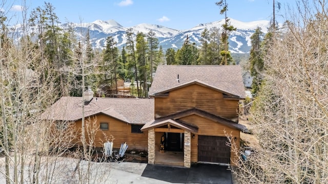 119 Royal Tiger Rd, Breckenridge, CO 80424 - view of front of property featuring a mountain view, a garage, stone siding, a shingled roof, and a chimney